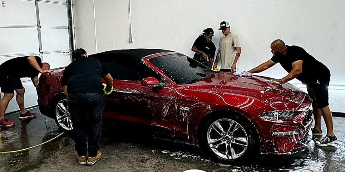 Detailing team performing the multi-step coating process on a sports car